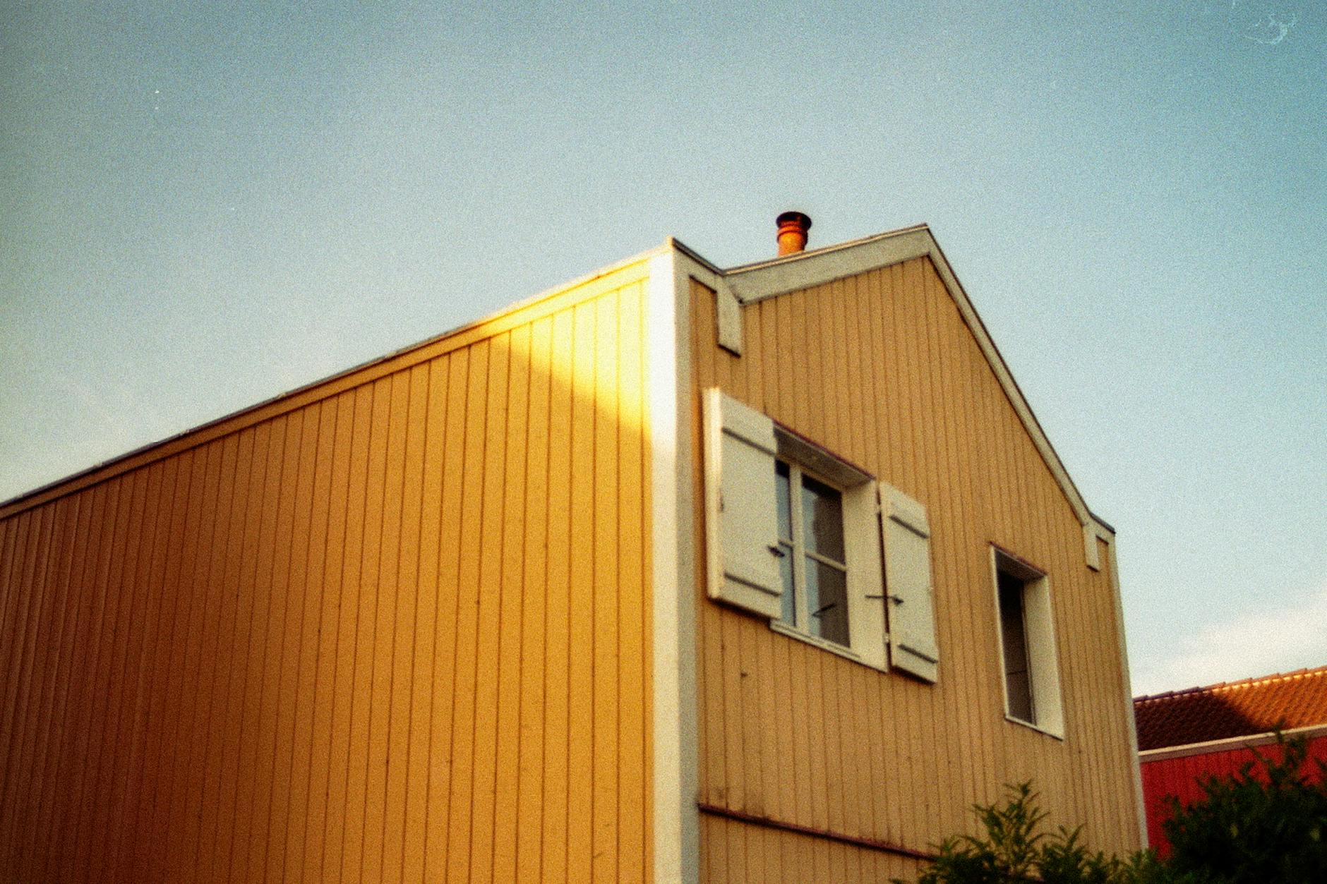 Vintage-style low angle view of a house facade with warm light and open shutter window.
