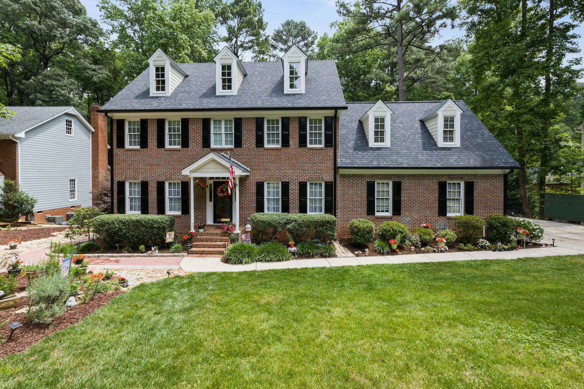 Stunning colonial-style brick house with lush garden and classic architecture.