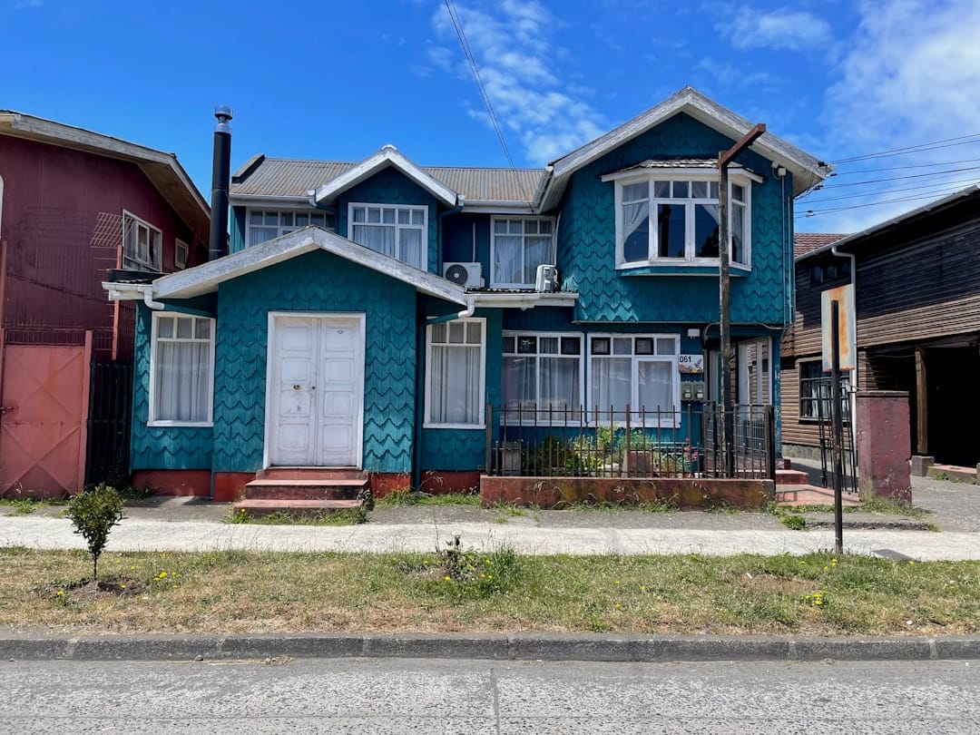 A two-story teal house with white trim.